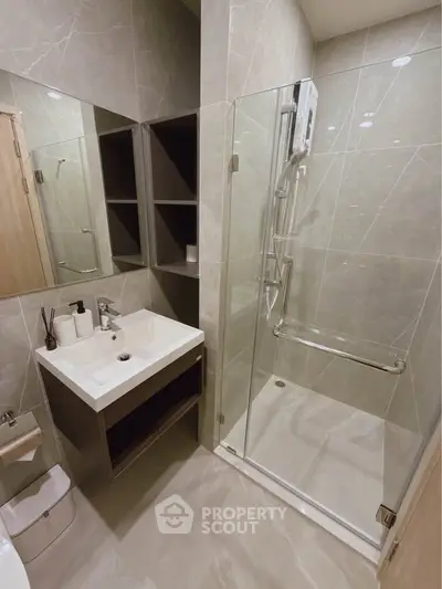 Modern bathroom with glass shower and sleek vanity in stylish apartment.