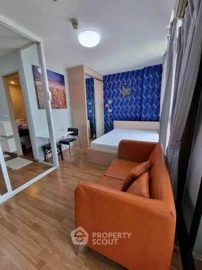 Modern studio apartment with stylish decor and cozy furnishings, featuring a vibrant blue accent wall and wooden flooring.