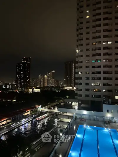 Stunning night view of city skyline with illuminated pool and high-rise buildings.