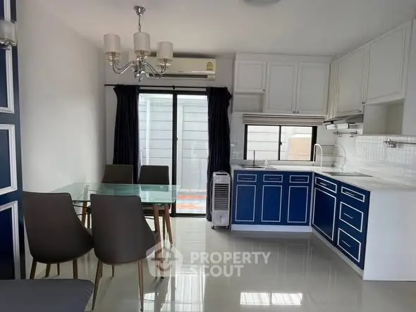 Modern kitchen with blue cabinets and dining area, featuring sleek design and natural light.