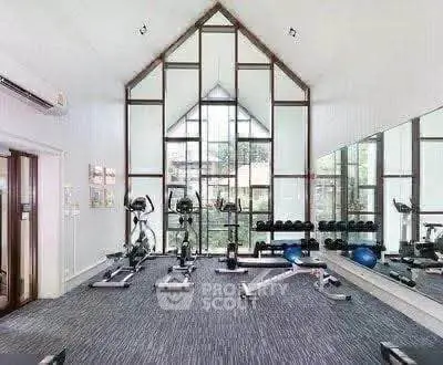 Spacious gym with modern equipment and large windows in luxury real estate property.