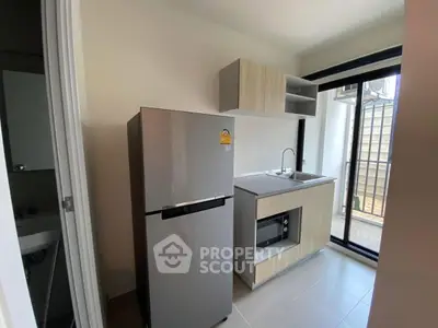 Modern compact kitchen with stainless steel fridge and built-in oven, perfect for urban living.