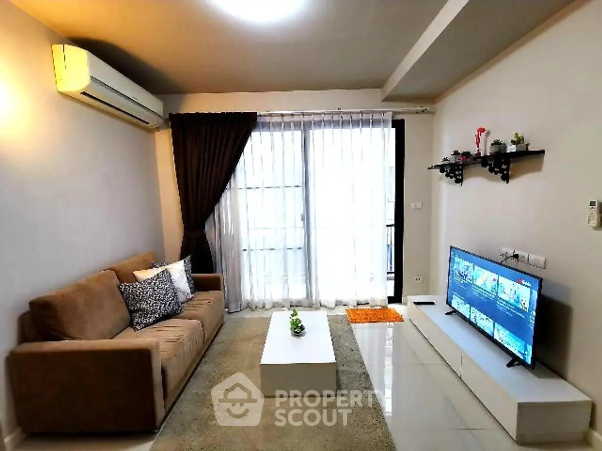 Modern living room with cozy sofa and large TV, featuring elegant decor and natural light.