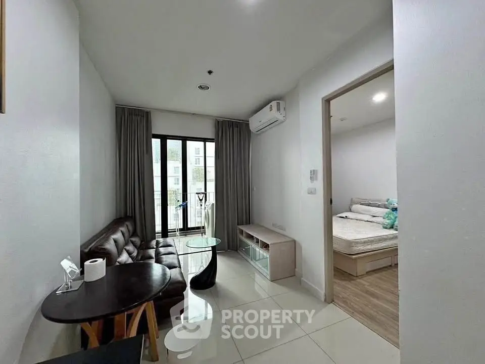 Modern living room with sleek furniture and access to a cozy bedroom, featuring a small balcony view.