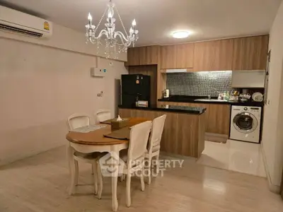 Chic open-layout kitchen with dining area, featuring modern appliances and elegant chandelier.