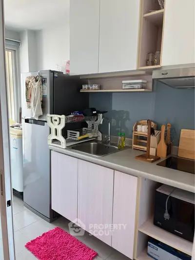 Modern compact kitchen with sleek cabinetry and stainless steel appliances in a cozy apartment.