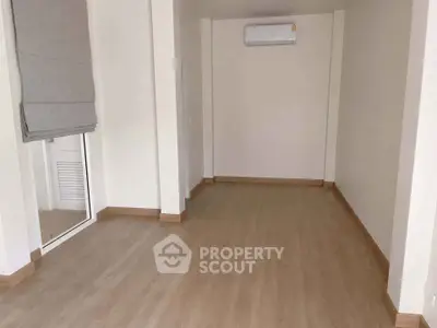 Spacious empty room with wooden flooring and air conditioning, perfect for customization.