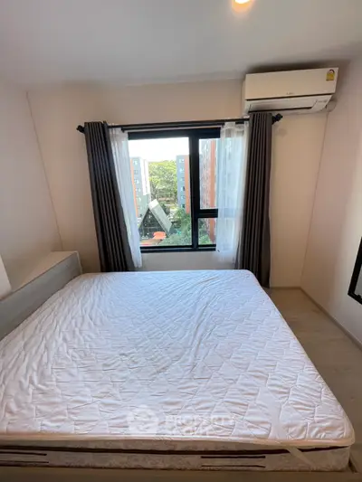 Cozy bedroom with large window and air conditioning, offering a pleasant view of the cityscape.