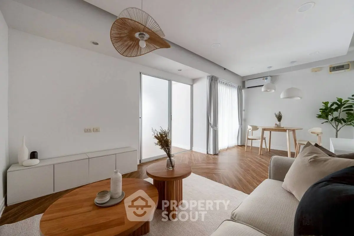 Modern living room with elegant decor and natural light, featuring wooden flooring and stylish furniture.