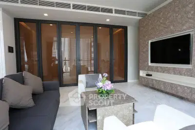 Modern living room with sleek design and large TV, featuring stylish furniture and elegant decor.