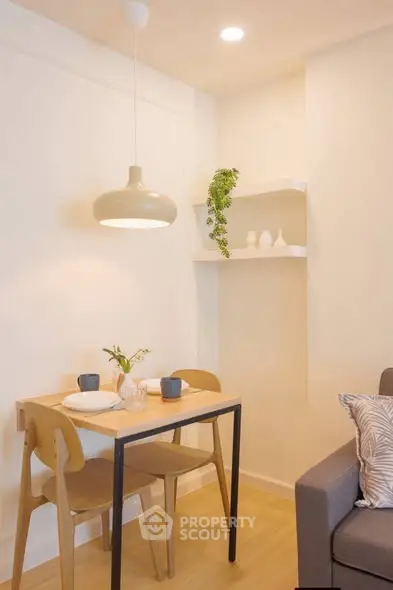 Cozy dining nook with modern table and chairs, stylish lighting, and decorative shelves in a bright apartment.