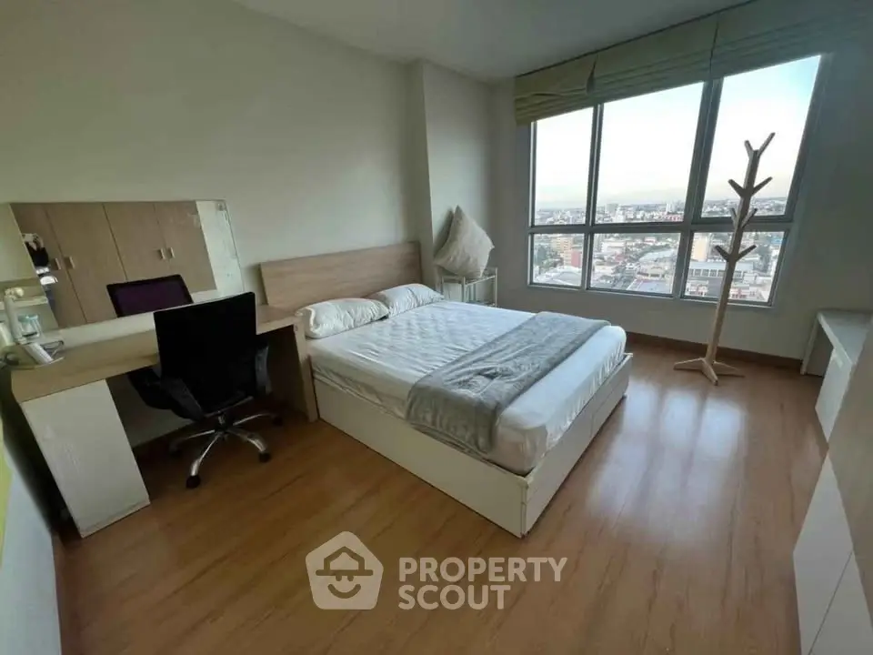 Spacious bedroom with large window offering stunning city views, modern furnishings, and ample natural light.