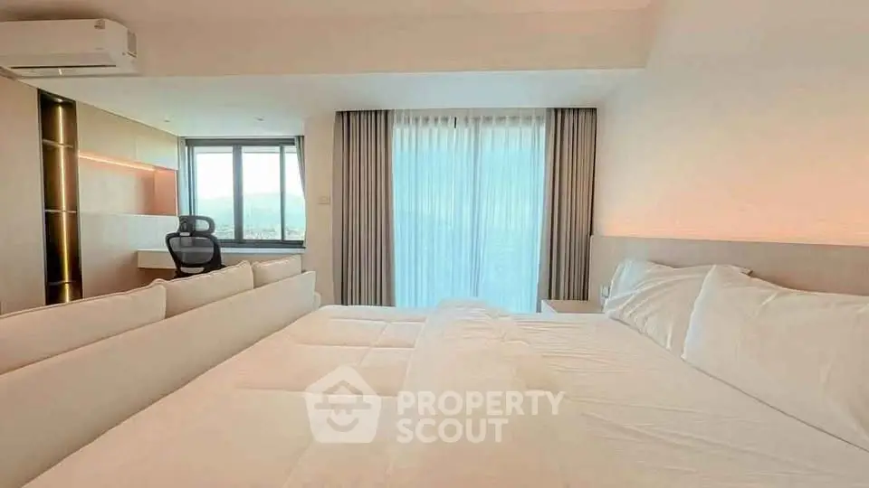 Spacious bedroom with modern decor and large windows offering natural light.