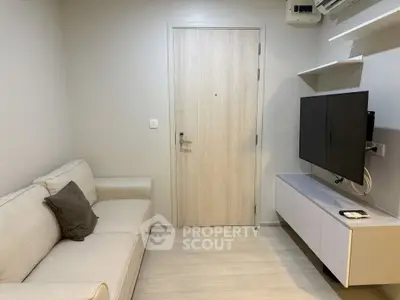 Modern living room with sleek TV setup and cozy sofa in a compact space.