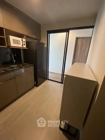Modern kitchen with sleek cabinetry, microwave, and refrigerator in a compact layout.