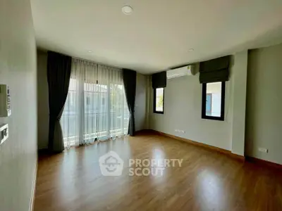Spacious empty living room with large windows and wooden flooring in modern home.