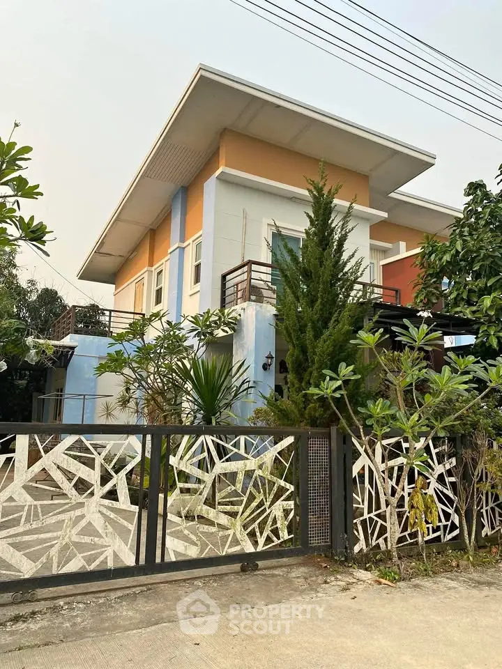Modern two-story house with unique geometric gate and lush greenery