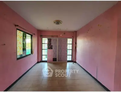 Spacious pink-walled room with large window and tiled floor, ideal for creative transformation.