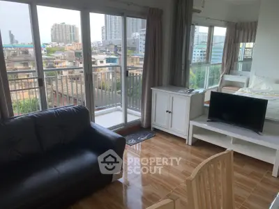 Modern studio apartment with city view, featuring a cozy living area, sleek black sofa, and large windows.
