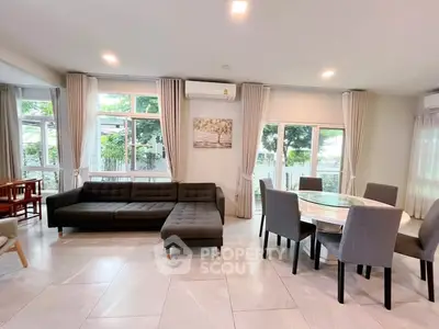 Spacious modern living room with large windows and elegant dining area