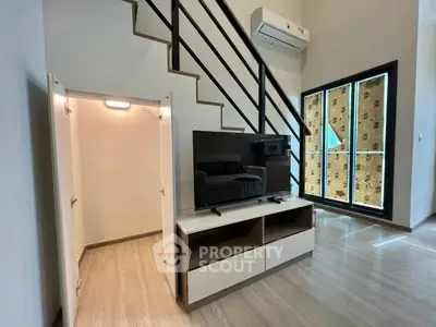 Modern living room with sleek staircase and stylish TV unit in a bright, airy space.
