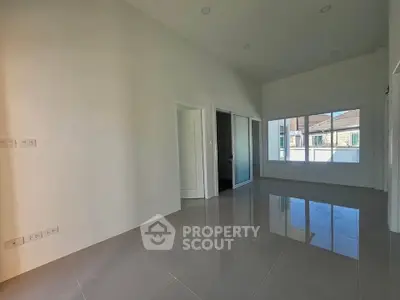 Spacious empty room with large window and glossy tiled floor