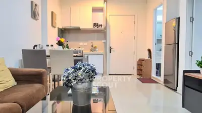 Modern open-plan living room with kitchen and dining area, featuring stylish decor and bright lighting.