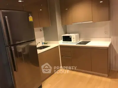 Modern kitchen with sleek cabinetry and stainless steel fridge in a cozy apartment.