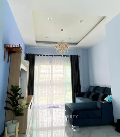 Elegant living room with chandelier and large window, featuring modern furniture and stylish decor.