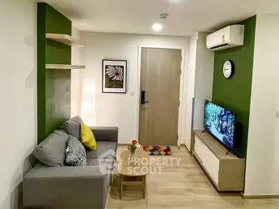Modern living room with green accent wall, cozy sofa, and wall-mounted TV in stylish apartment.