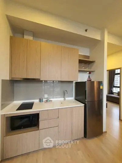 Modern kitchen with sleek cabinetry and stainless steel fridge in open layout apartment