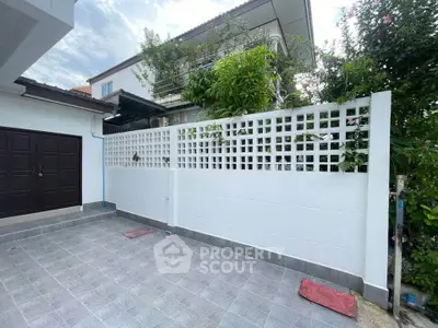 Charming residential exterior with spacious tiled patio and lush greenery