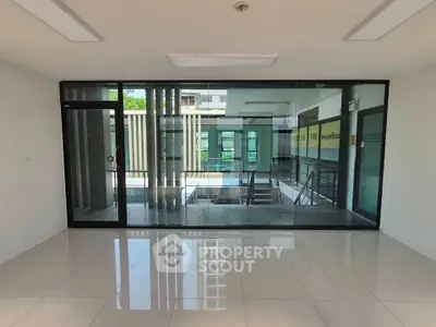 Spacious modern office space with glass walls and polished floors, ideal for professional settings.