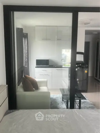 Modern studio apartment with glass partition, cozy living area, and compact kitchen featuring sleek appliances.