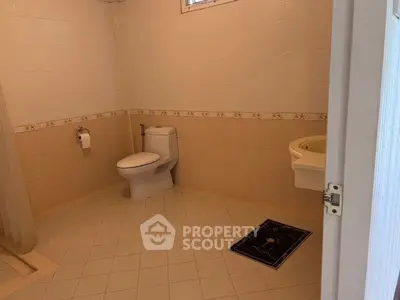 Spacious bathroom with modern fixtures and tiled flooring in a real estate property.