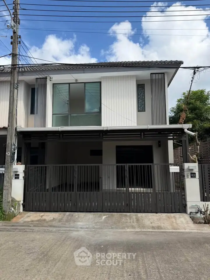Modern two-story house with sleek design and gated entrance, perfect for family living.