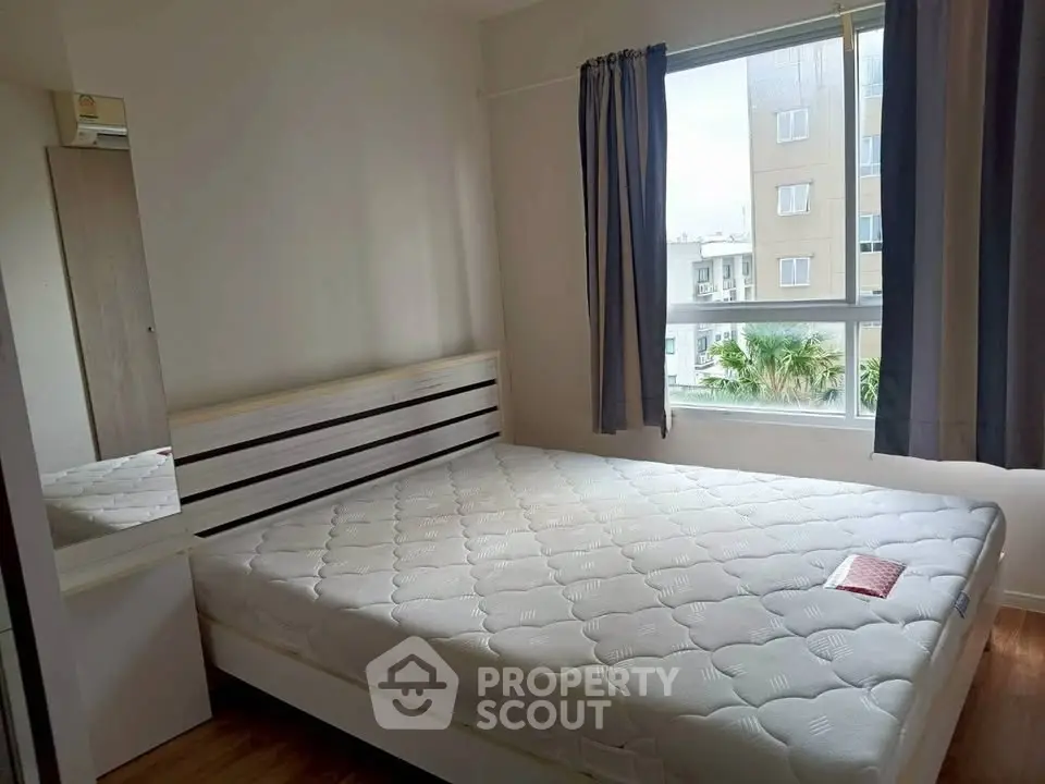 Cozy bedroom with large window and modern furnishings in a bright apartment.