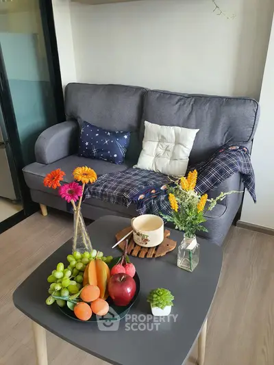 Cozy living room with stylish sofa, vibrant cushions, and fresh fruit on a modern coffee table.