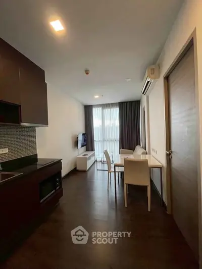 Modern living room with dining area and sleek kitchen in open layout apartment.