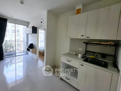 Modern apartment interior with kitchen and balcony view, featuring sleek cabinetry and bright natural light.