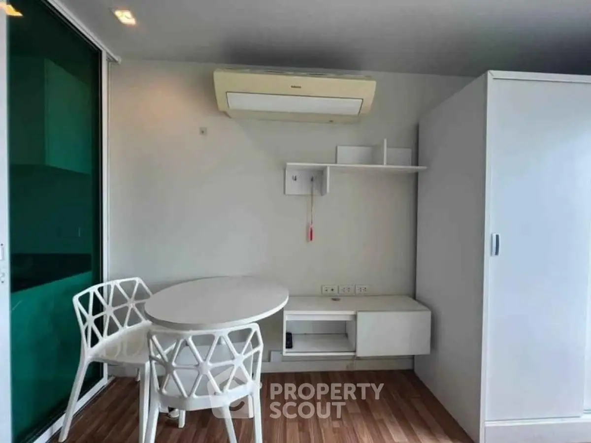 Modern minimalist interior with white furniture and wood flooring, featuring a compact dining area.