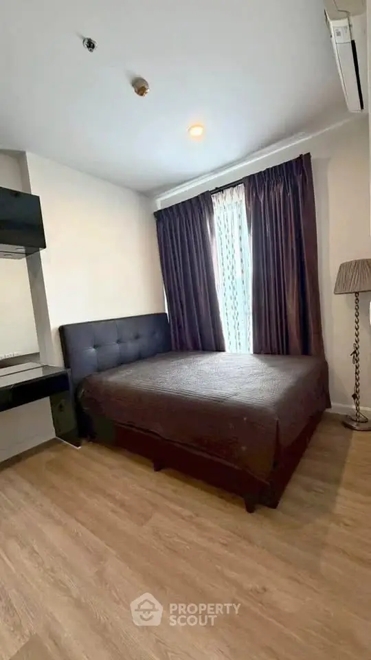 Cozy bedroom with modern decor and large window in a stylish apartment.