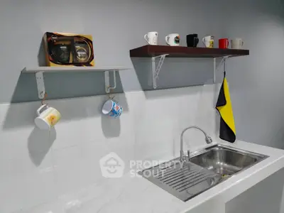 Modern kitchen with sleek sink and stylish mug display on shelves.