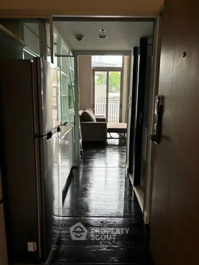 Modern apartment hallway leading to a cozy living area with natural light and sleek design.