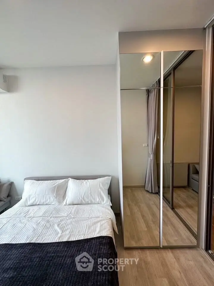 Modern bedroom with mirrored closet and cozy bedding in stylish apartment.