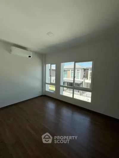 Spacious empty room with large windows and wooden flooring, perfect for customization.