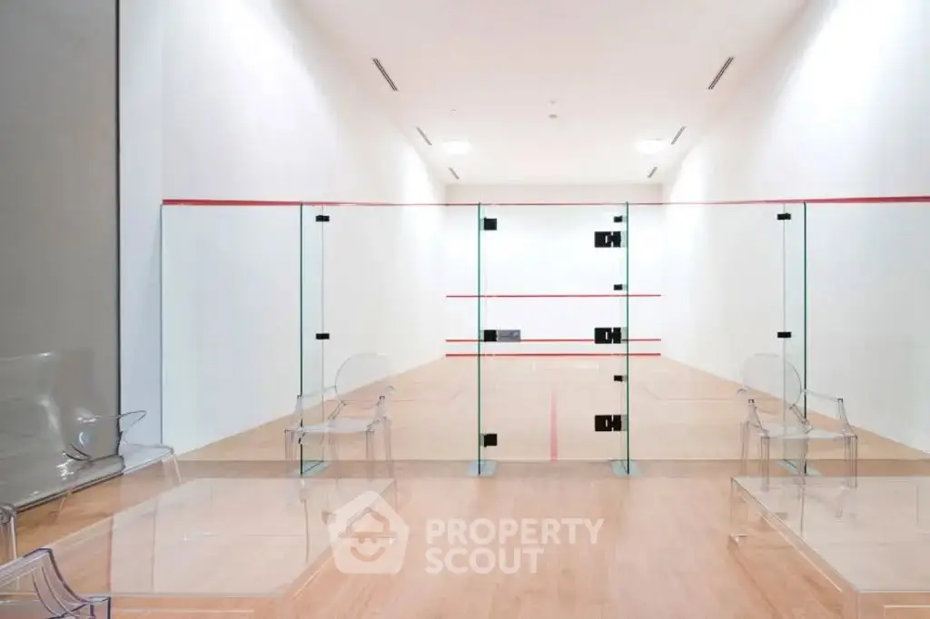 Modern squash court with glass walls and wooden flooring in luxury residential building.
