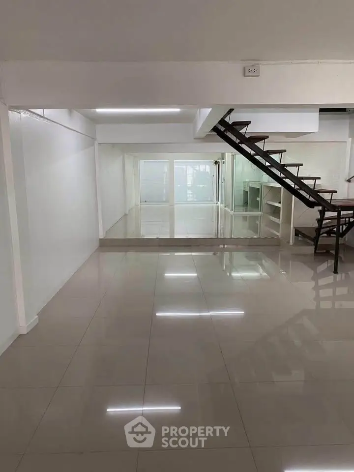 Spacious modern interior with sleek staircase and glossy tiled floors, perfect for contemporary living.