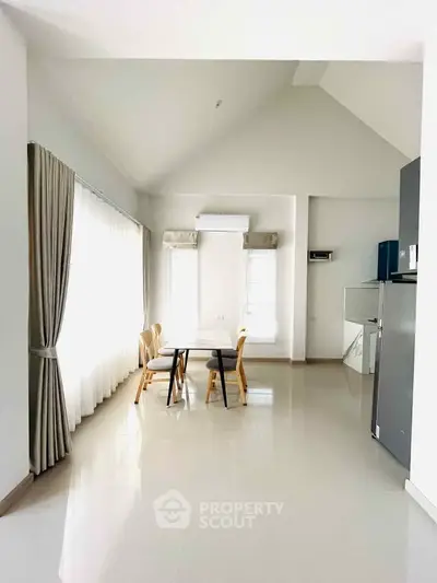Spacious dining area with high ceilings and natural light, featuring modern furniture and sleek flooring.