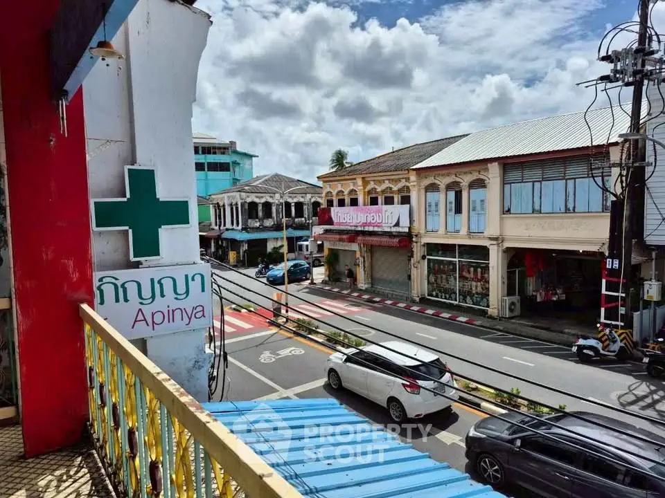 Charming street view from a balcony overlooking vibrant shops and historic architecture.